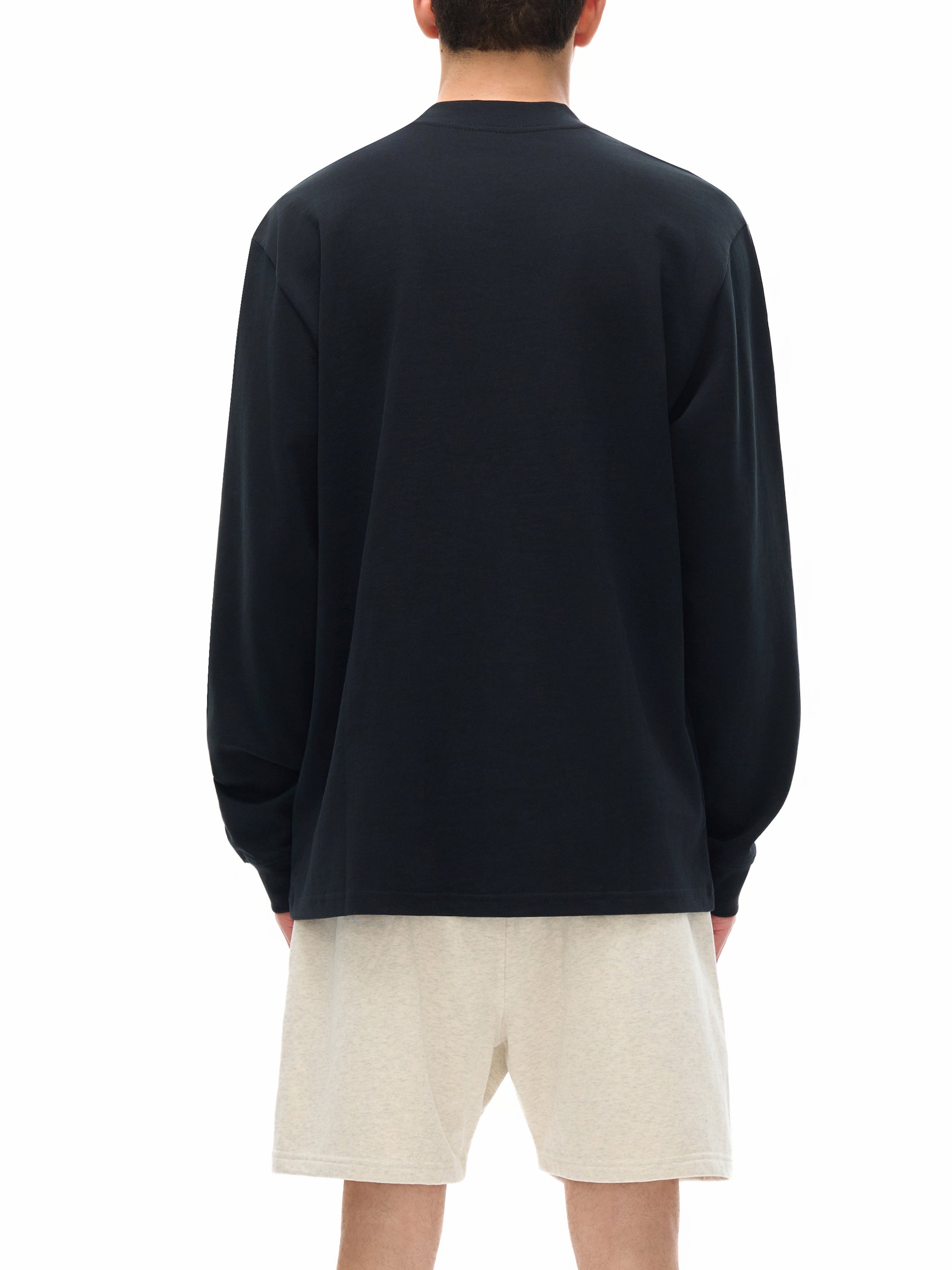 Person wearing a black sweatshirt and beige shorts on a white background