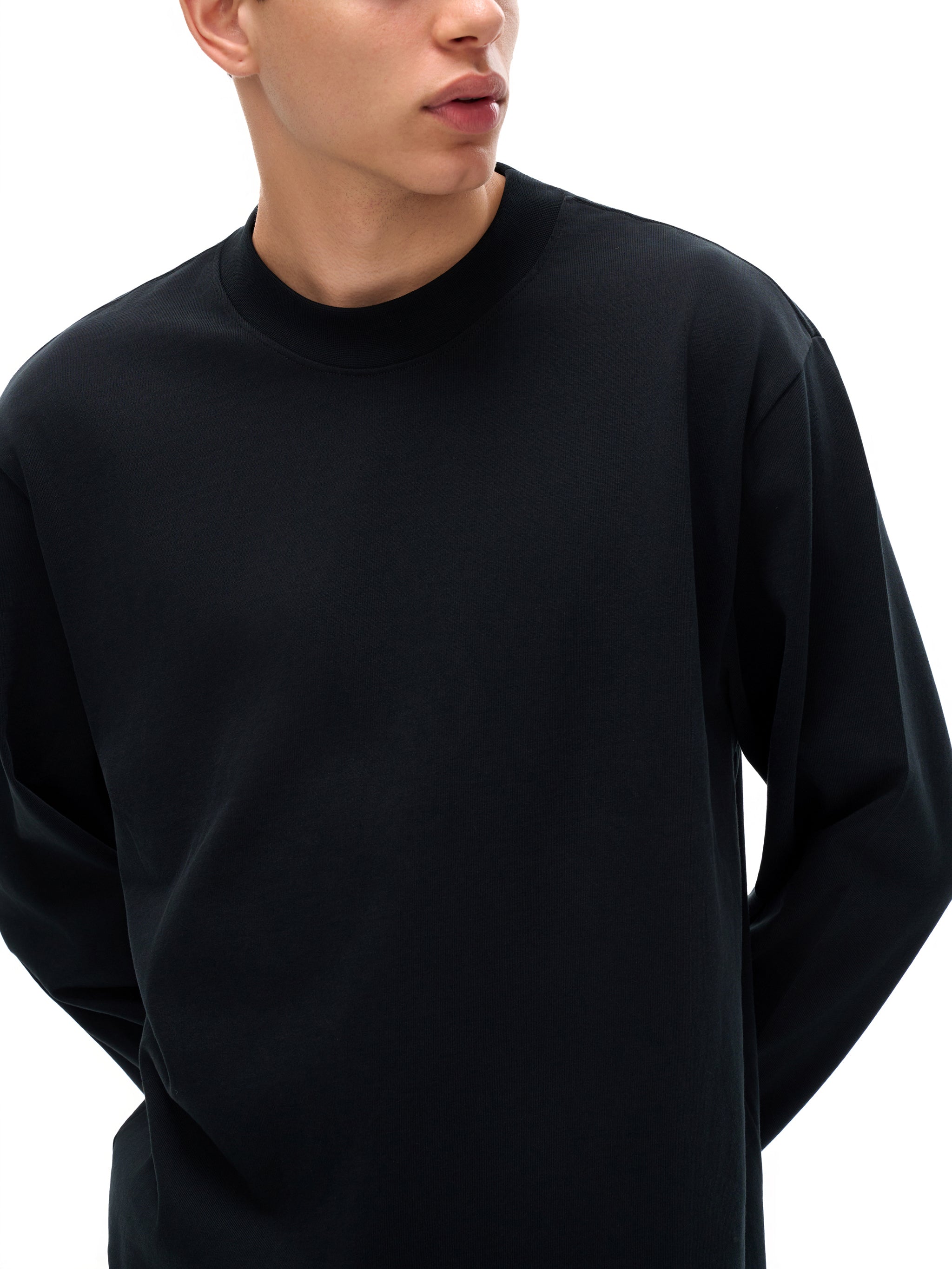Person wearing a black long-sleeve shirt on a white background